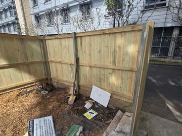 New treated pine palings beside paved areas.