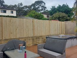 Treated pine paling fence on a stone wall
