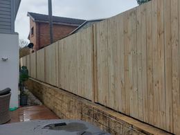 Treated pine paling fence on a sandstone retaining wall