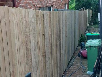New treated pine palings beside paved areas.