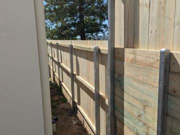 New treated pine palings beside paved areas.