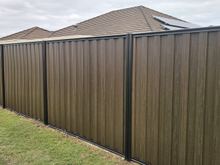 Installed Espresso woodgrain steel fence with black posts and rails beside a lawn